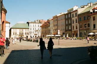 a group of people walking down a street next to tall buildings