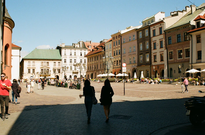 a group of people walking down a street next to tall buildings
