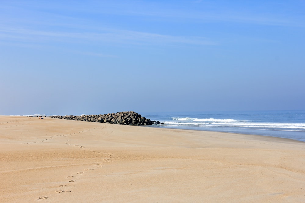 a sandy beach next to the ocean under a blue sky