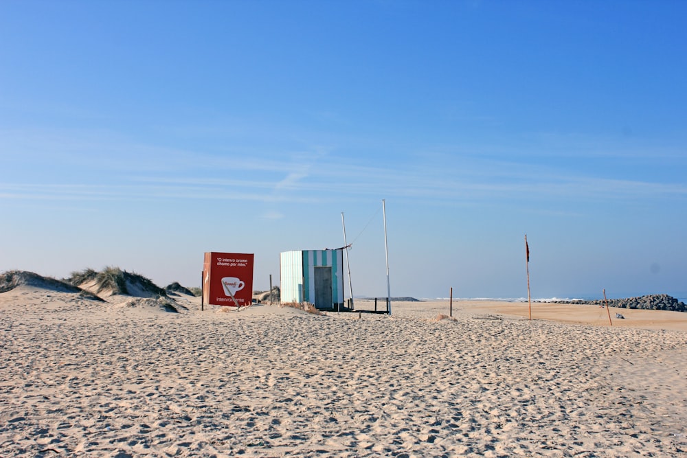 une plage avec un panneau rouge et un bâtiment bleu