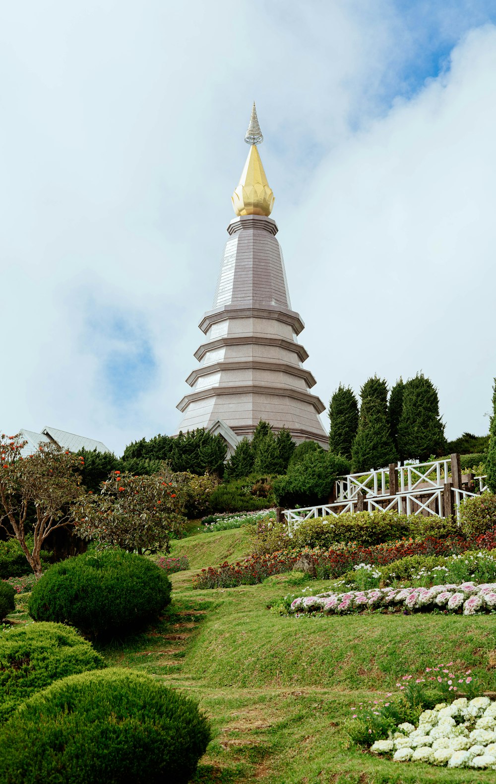 uma torre muito alta com um topo dourado no meio de um jardim