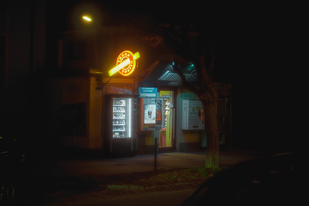 una calle oscura por la noche con un letrero de neón