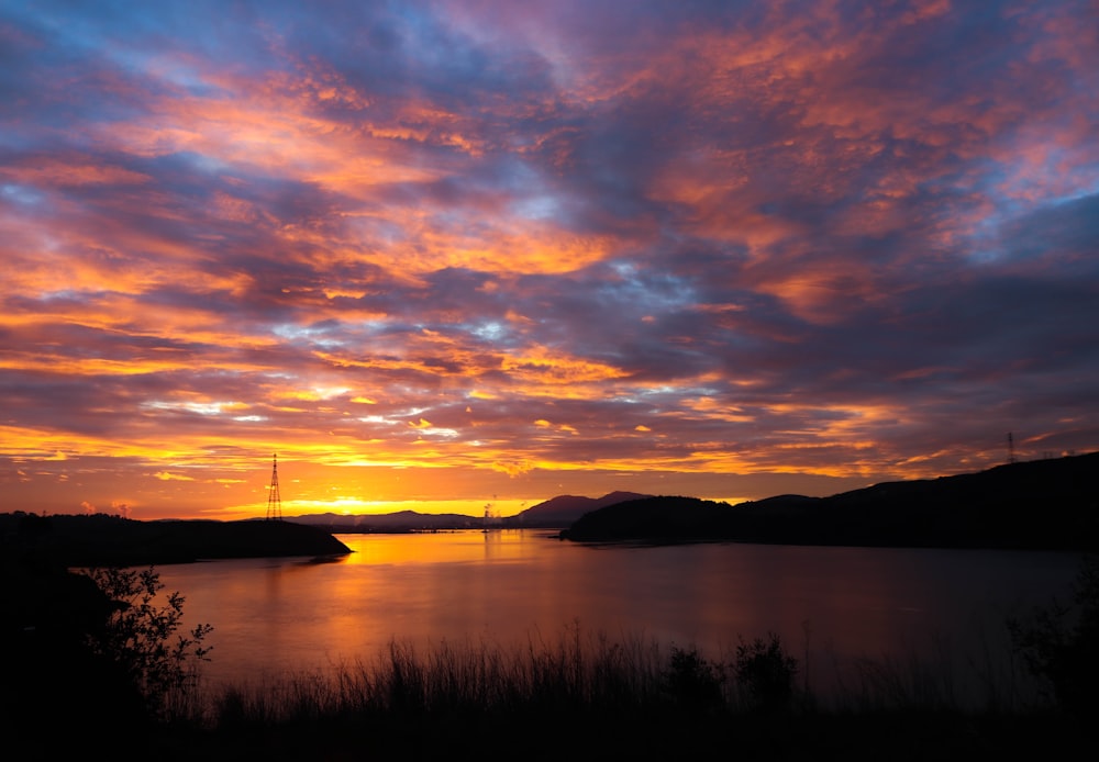 a sunset over a body of water with mountains in the background