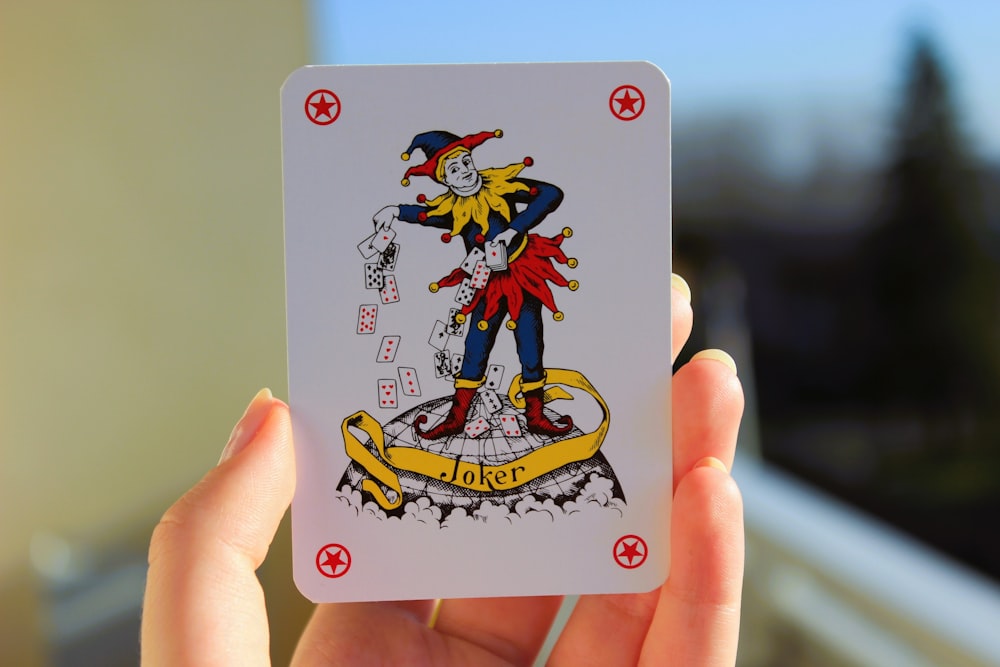 una mano che tiene una carta da gioco con l'immagine di un clown