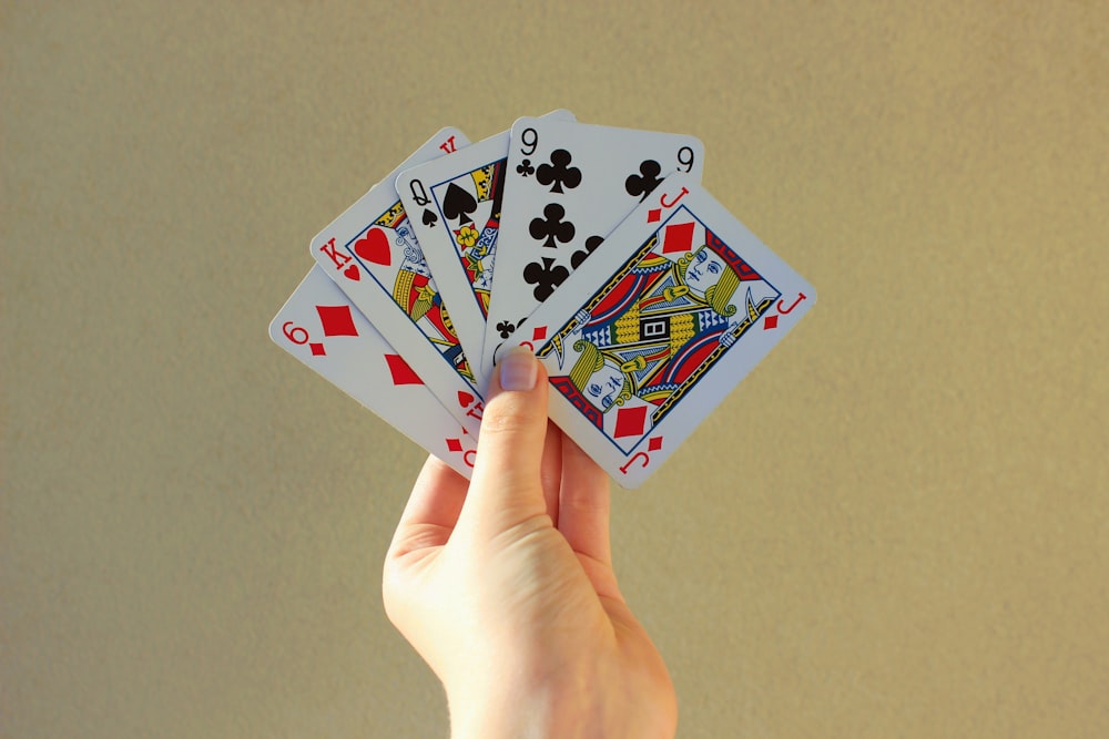 a person holding four playing cards in their hand