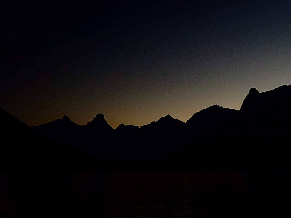 the silhouette of a mountain range against a dark sky