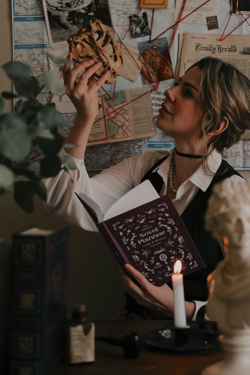 a woman holding a book in front of a candle