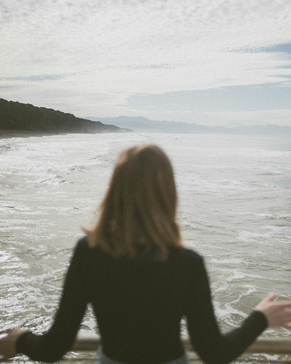 a woman standing on a balcony looking out at the ocean