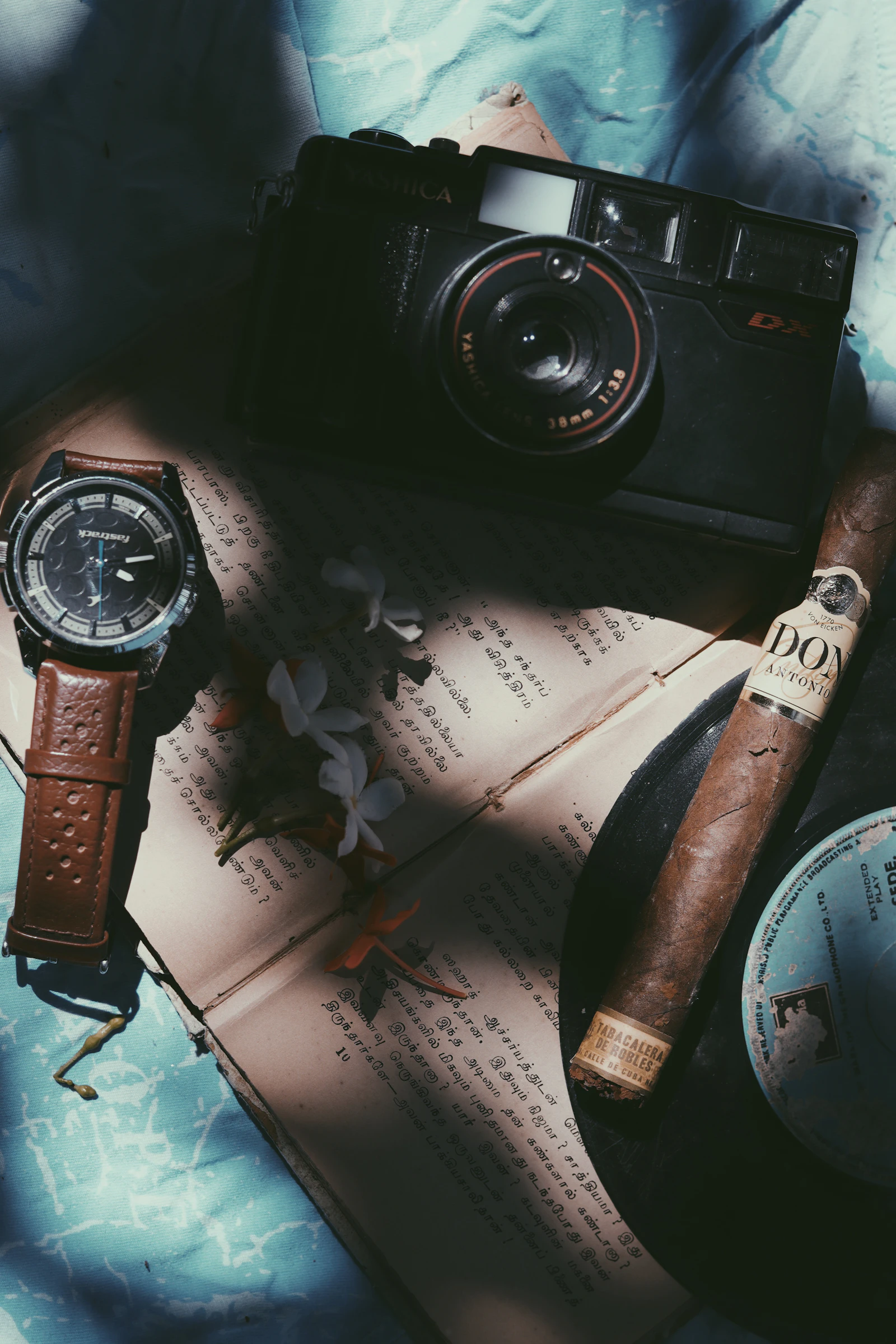 Camera, watch, cigar, and book arranged as symbols of a new chapter