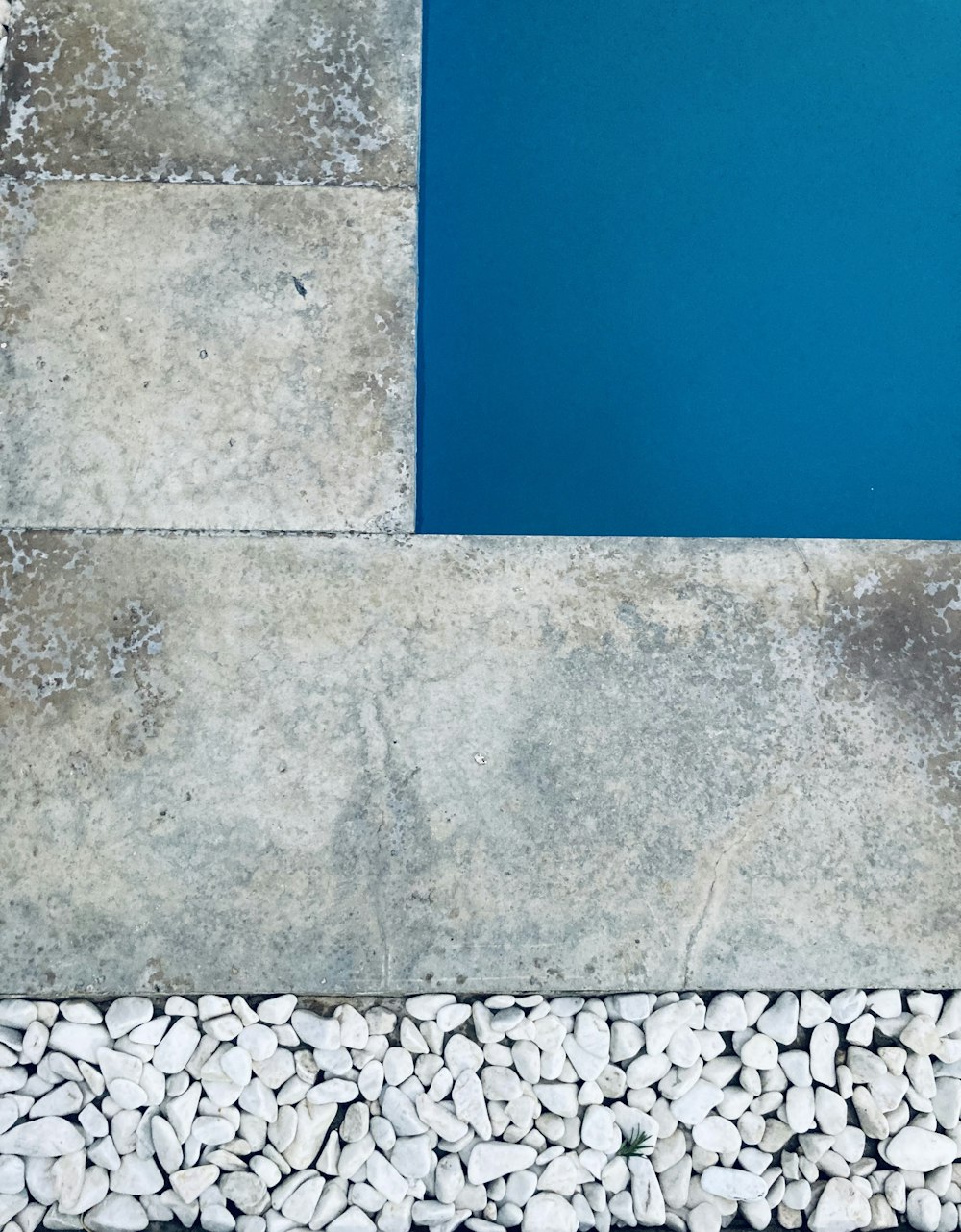 a blue pool surrounded by white rocks and gravel