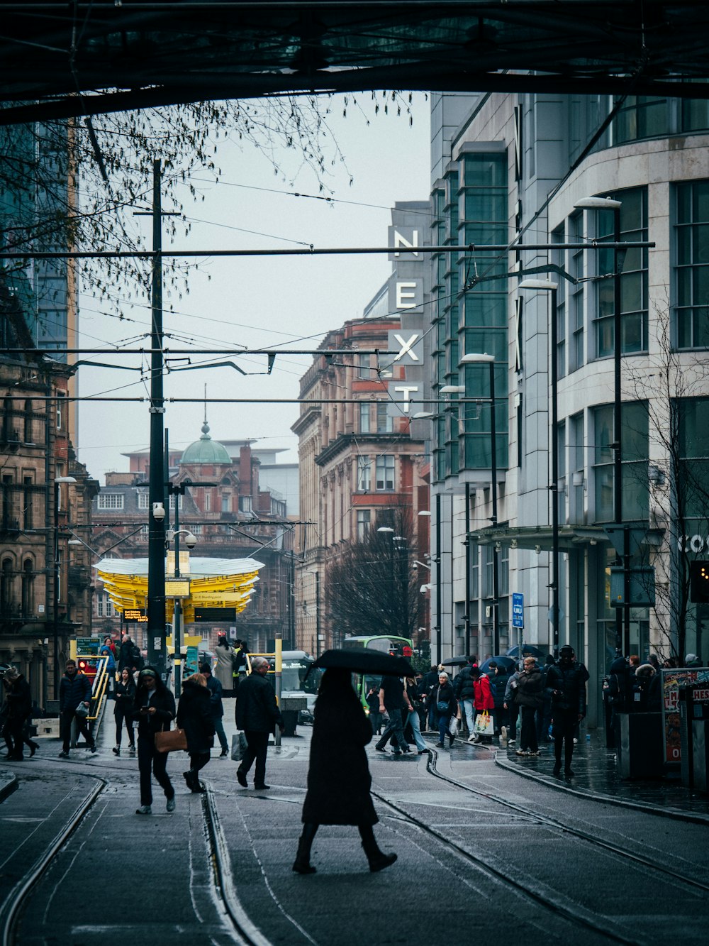 a group of people walking down a street next to tall buildings