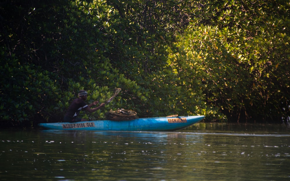 a man in a blue kayak paddles through the water