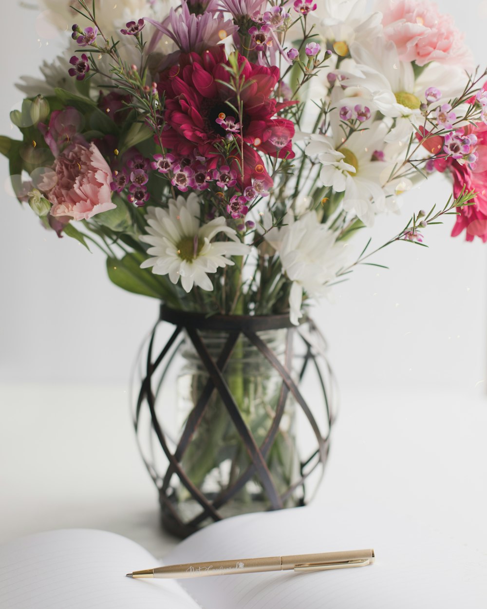 eine Vase gefüllt mit Blumen neben einem aufgeschlagenen Buch