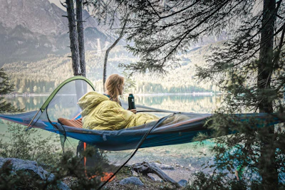 a woman sitting in a hammock with a bottle of beer