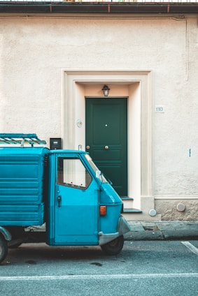 a small blue truck parked in front of a building