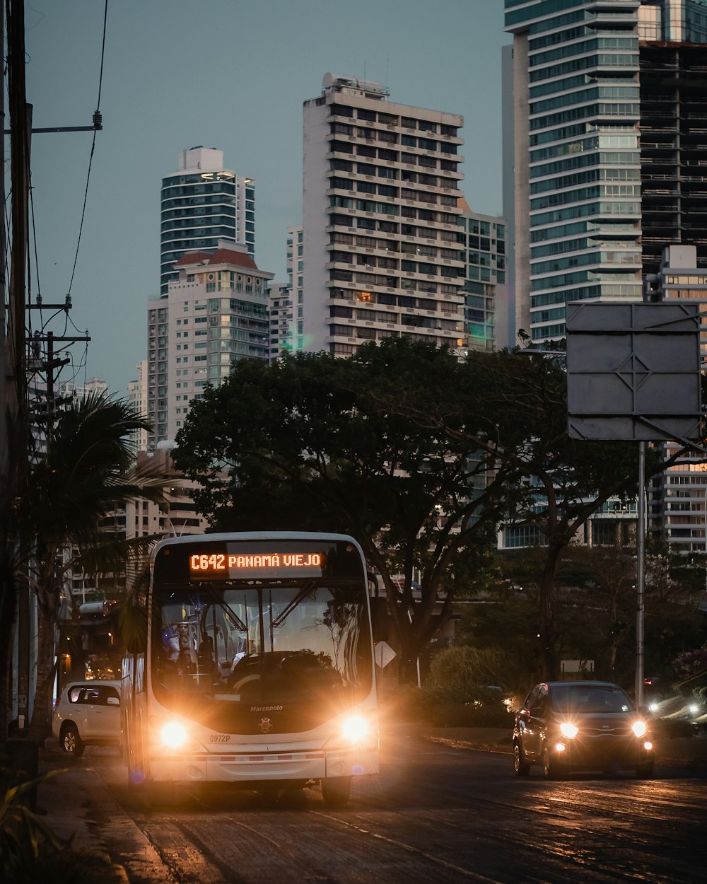 a city bus driving down a street with tall buildings in the background