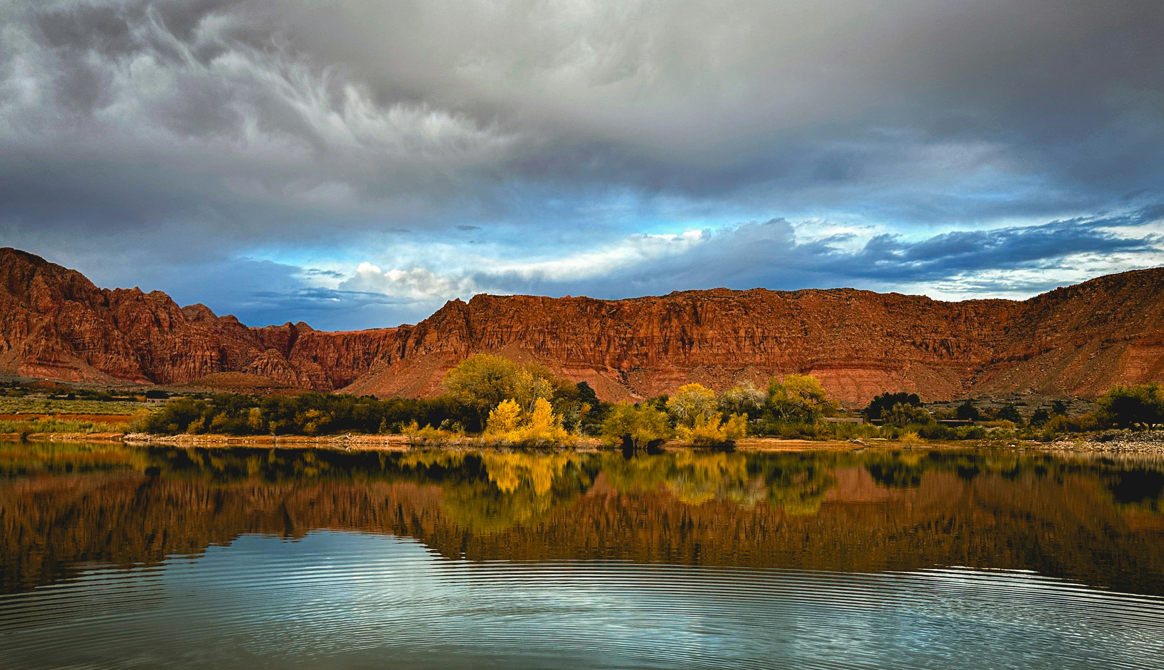 a body of water surrounded by mountains under a cloudy sky