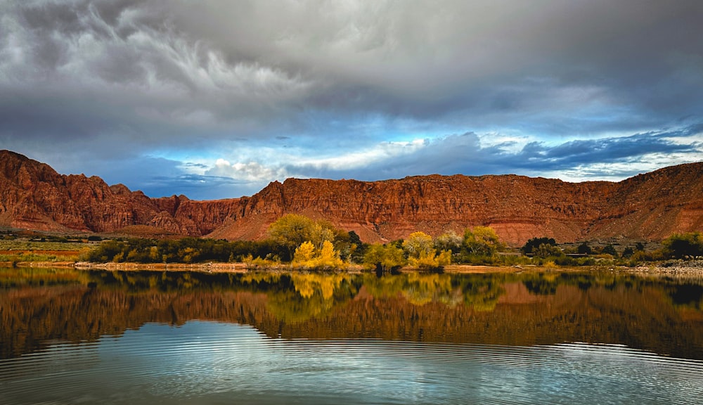 a body of water surrounded by mountains under a cloudy sky