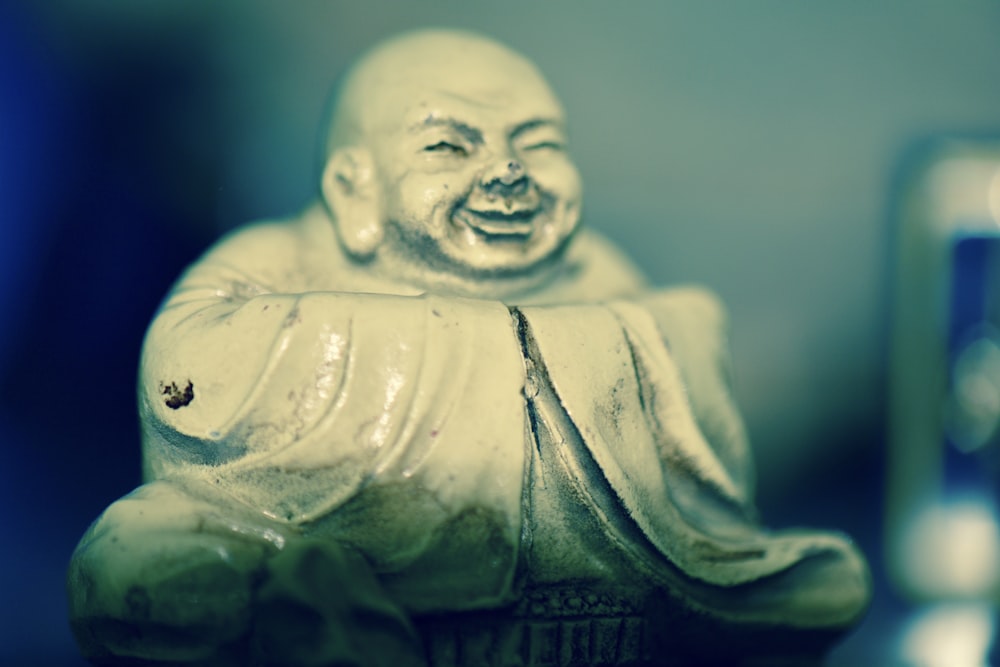 a statue of a laughing buddha next to a cell phone