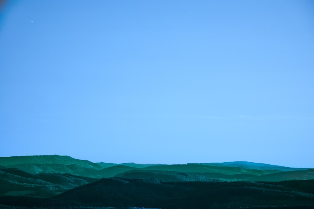 a view of a mountain range with a plane flying in the sky