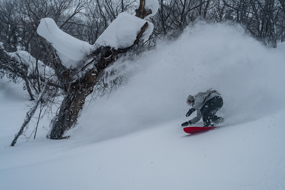 Un hombre montando una tabla de snowboard por una pendiente cubierta de nieve