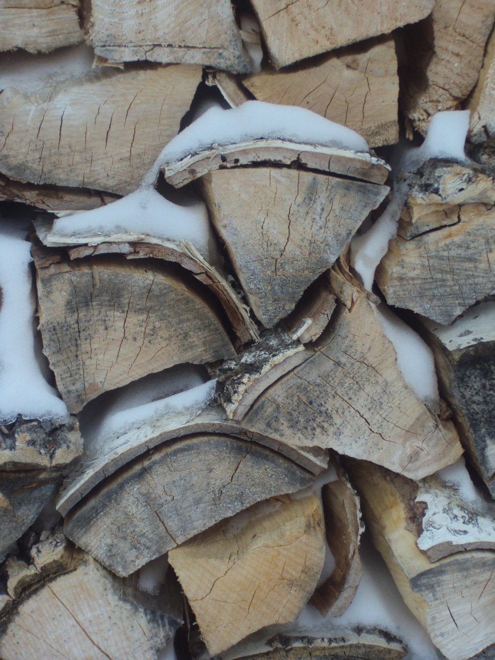 a pile of cut logs sitting on top of snow covered ground