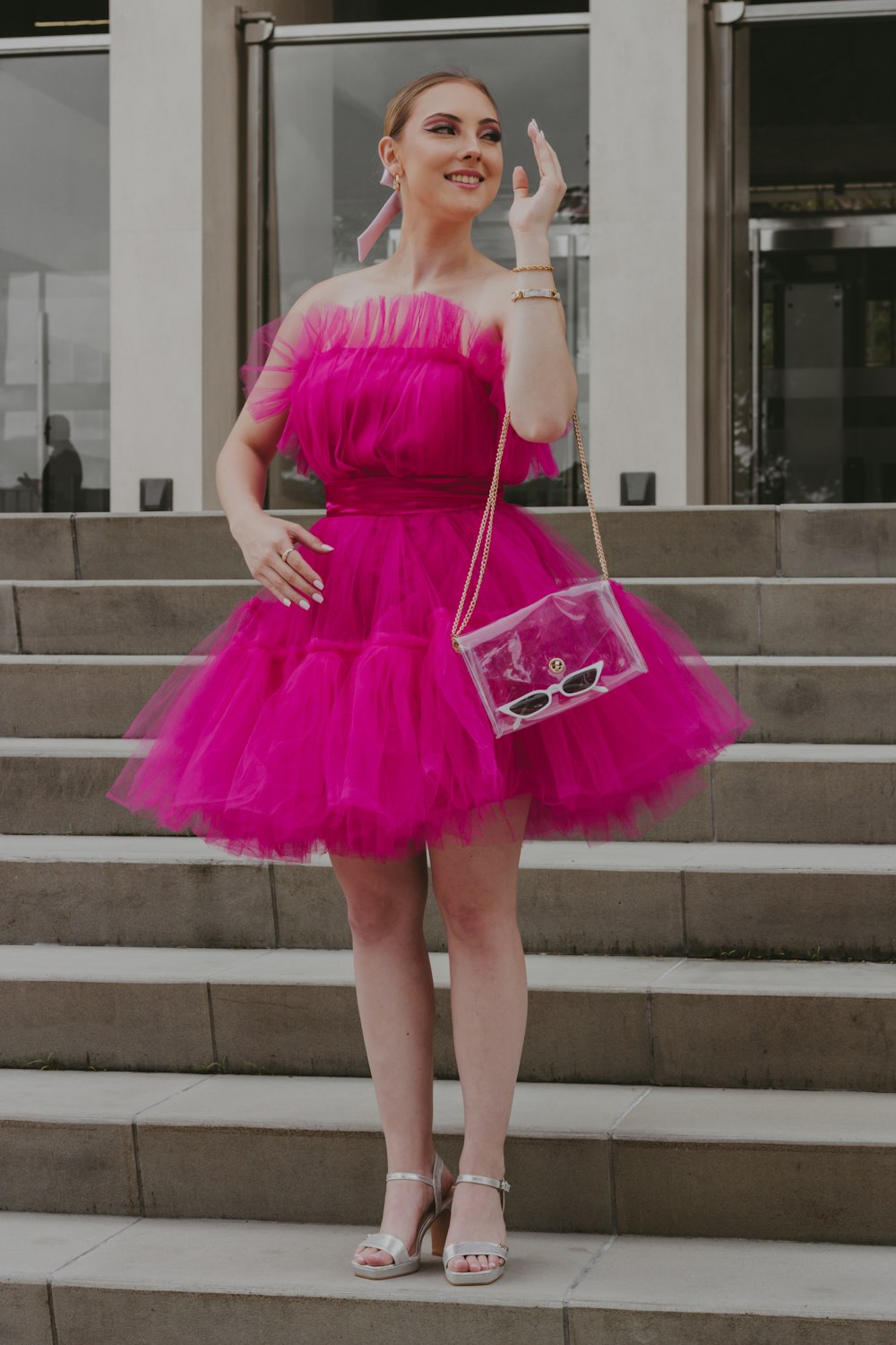 a woman in a pink dress is standing on some steps