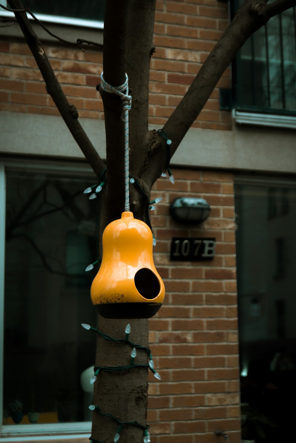 a yellow bell hanging from a tree in front of a building