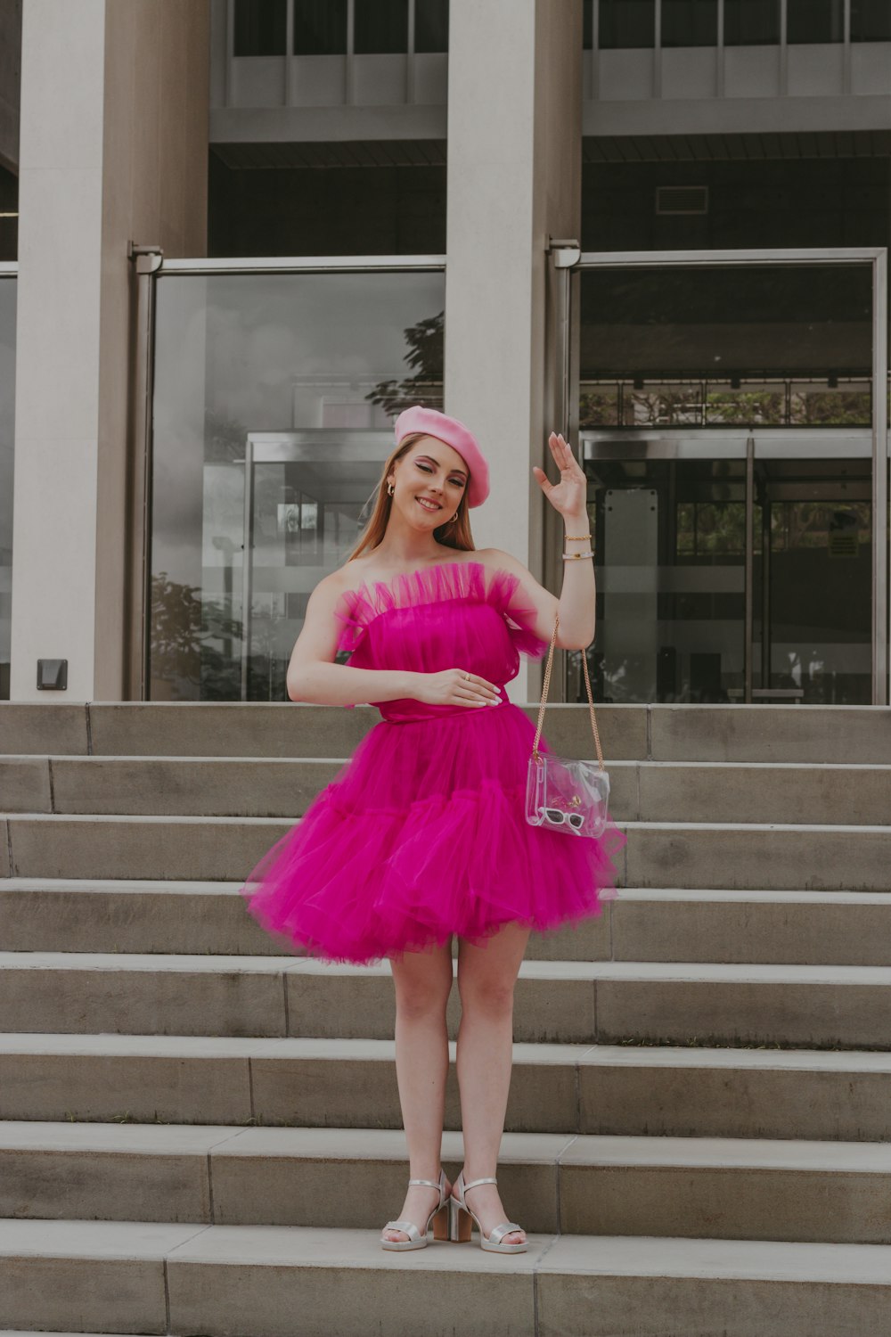 a woman in a pink dress is standing on some steps