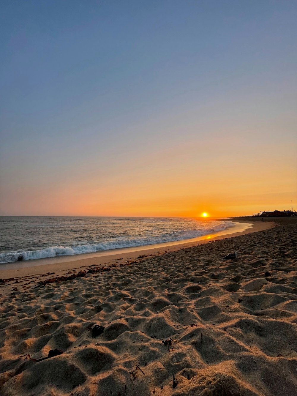 the sun is setting over the ocean on the beach