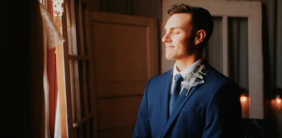 a man in a blue suit looking out a window