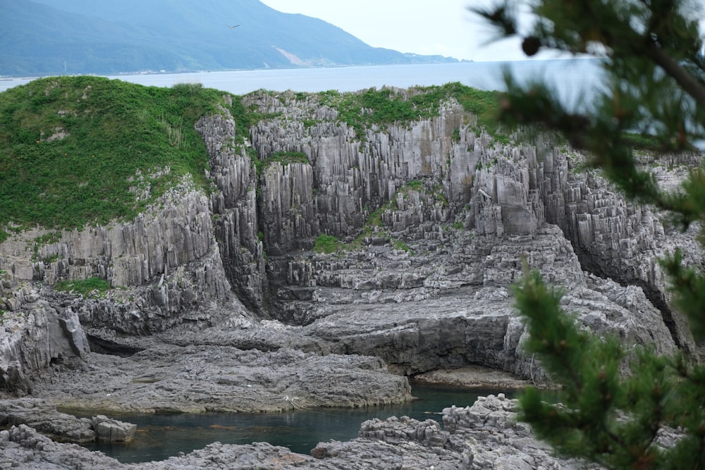 a rocky cliff with a body of water in the middle of it