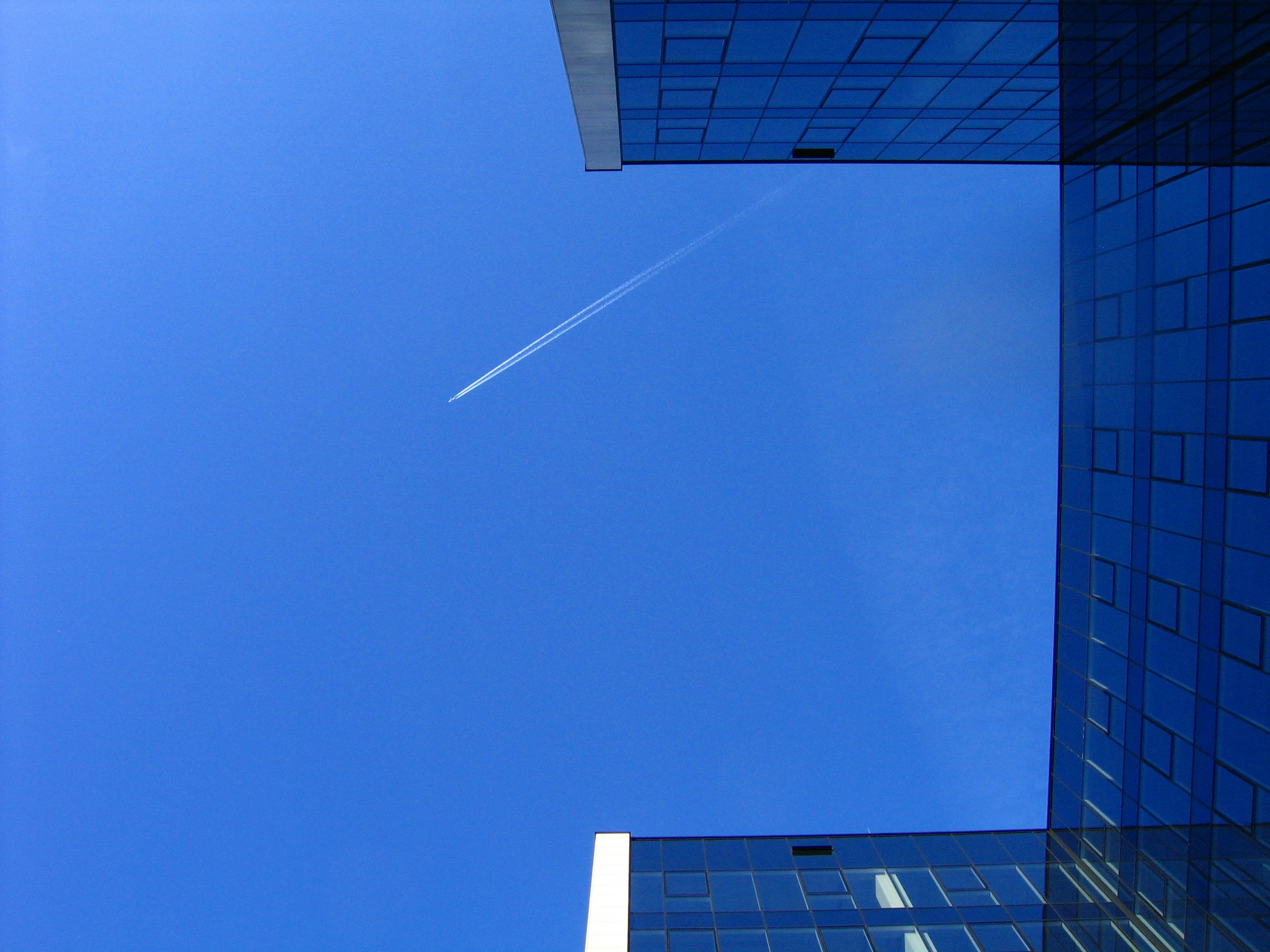un aereo vola nel cielo tra due edifici