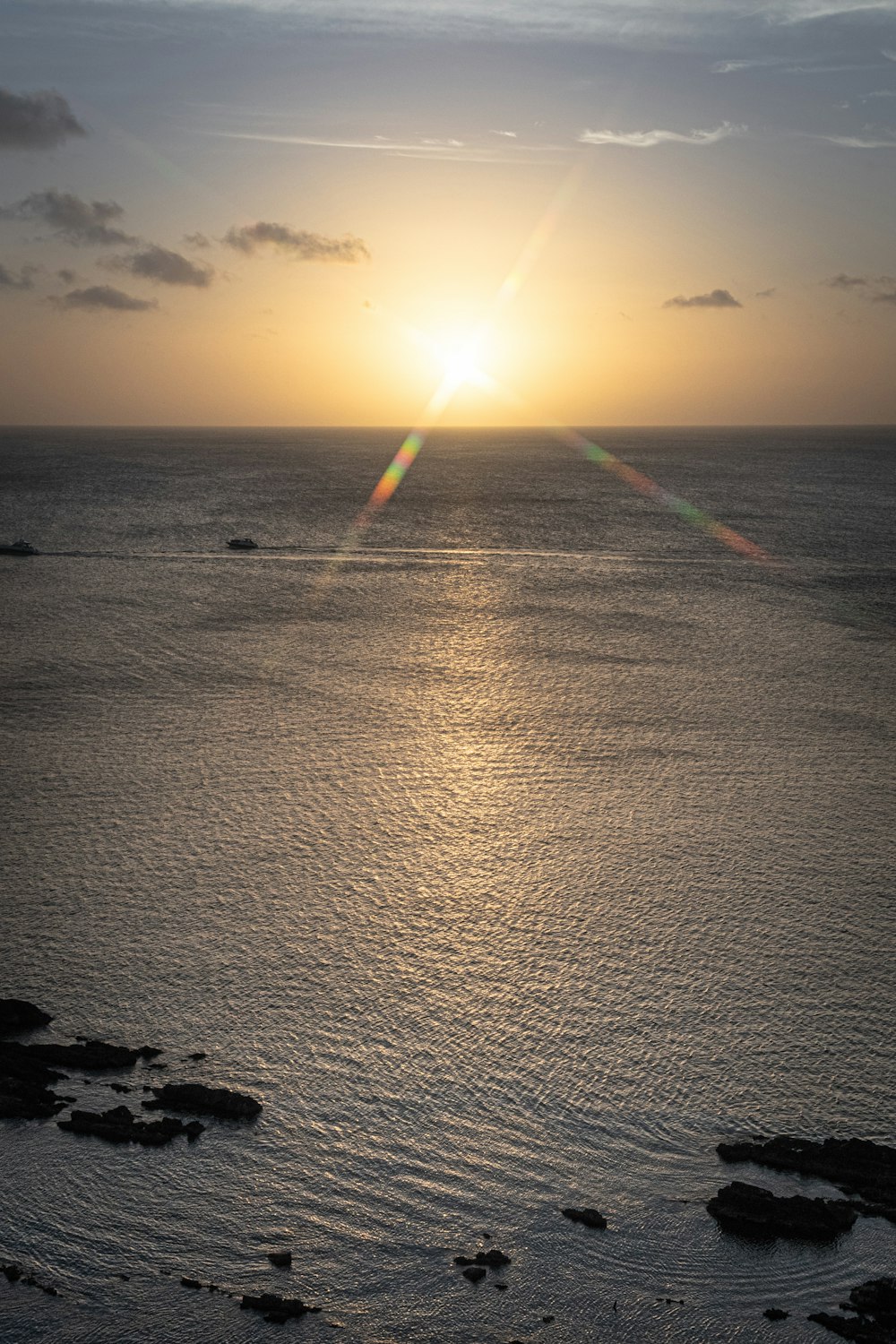 the sun is setting over the ocean on a cloudy day