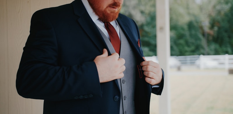 a man wearing a suit and tie standing in front of a window