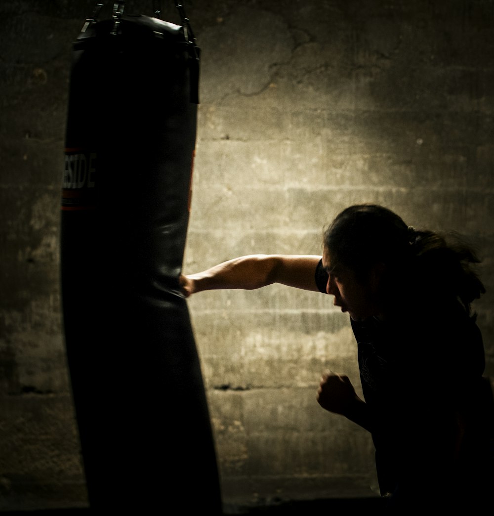 a woman is punching a punching bag in a dark room