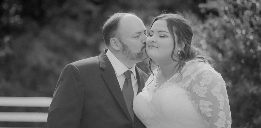 a bride and groom kissing in a black and white photo