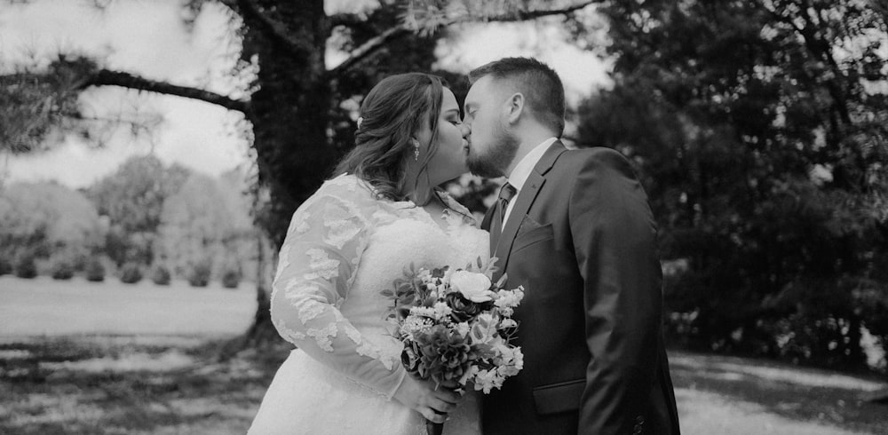 a bride and groom kissing in front of a tree