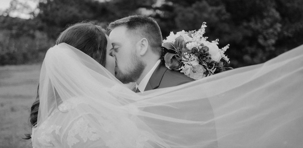 a bride and groom kissing under a veil