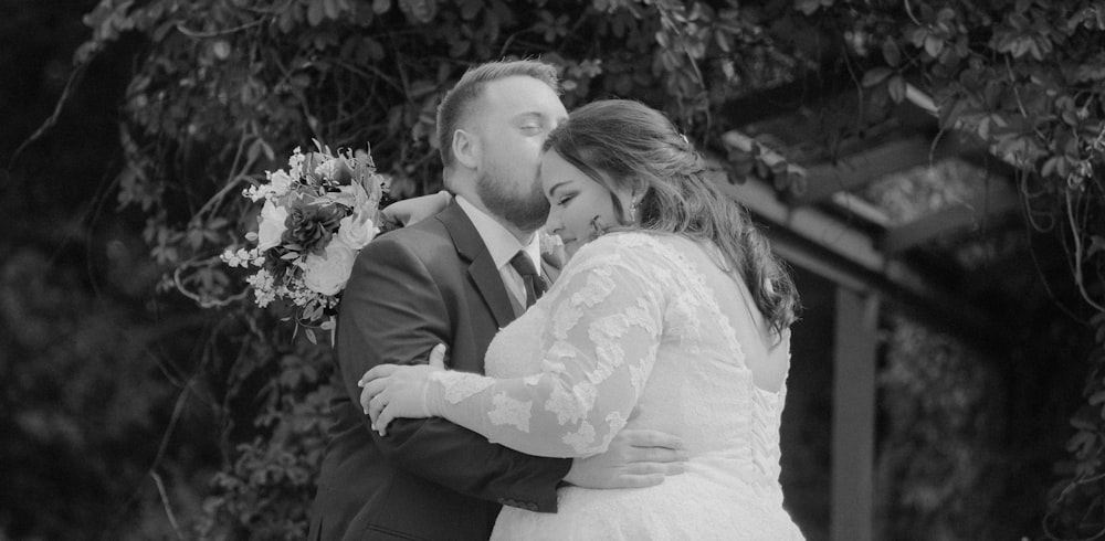 a bride and groom kissing in front of a tree