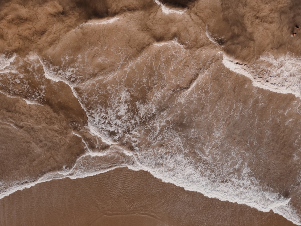 an aerial view of a sandy beach with waves