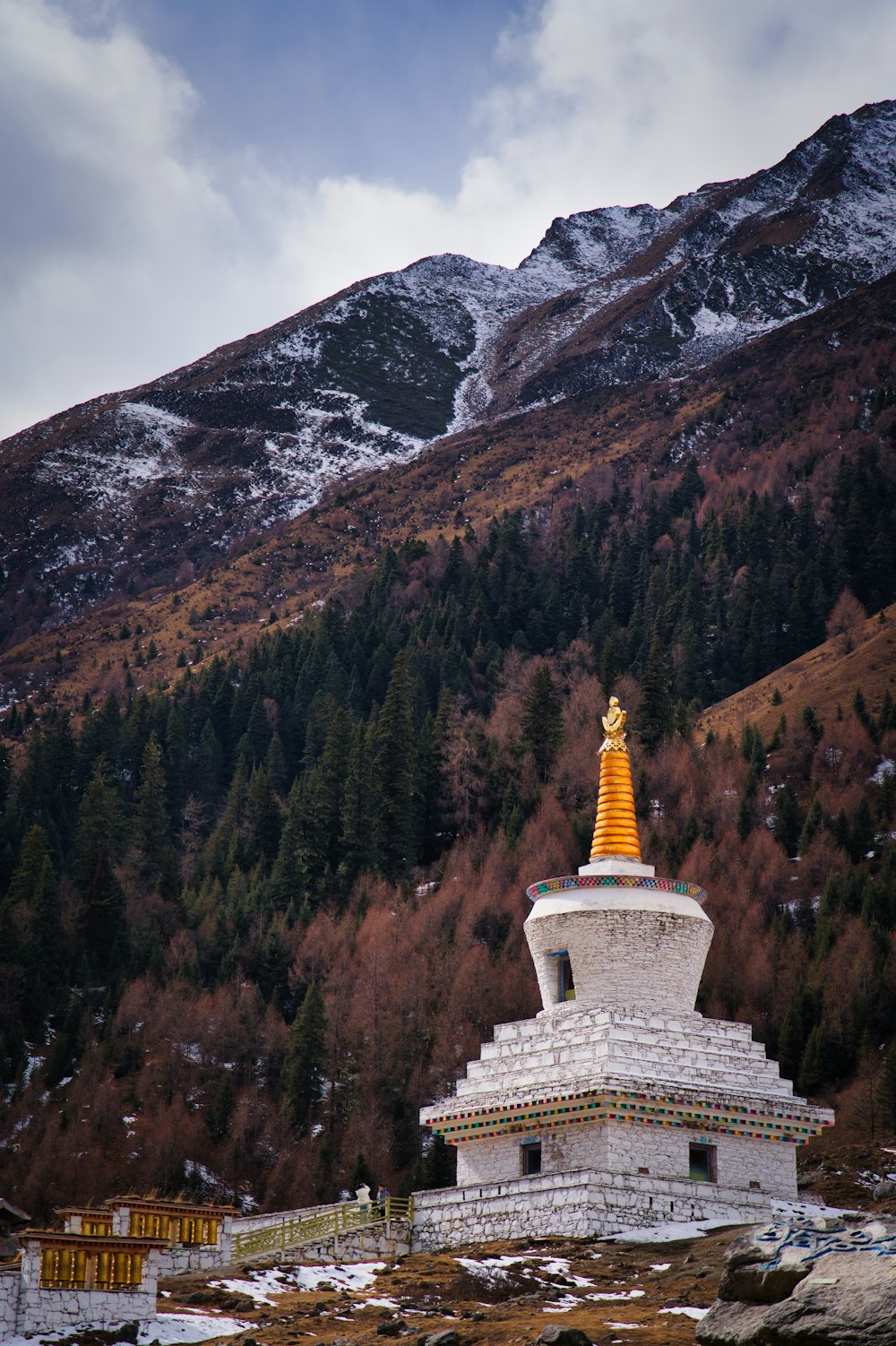 a white building with a golden top in front of a mountain