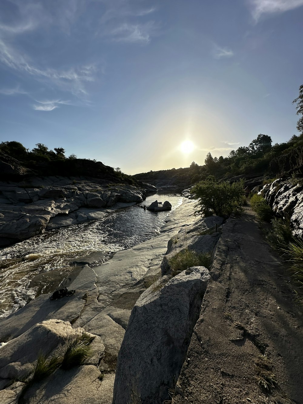 the sun is setting over a rocky river