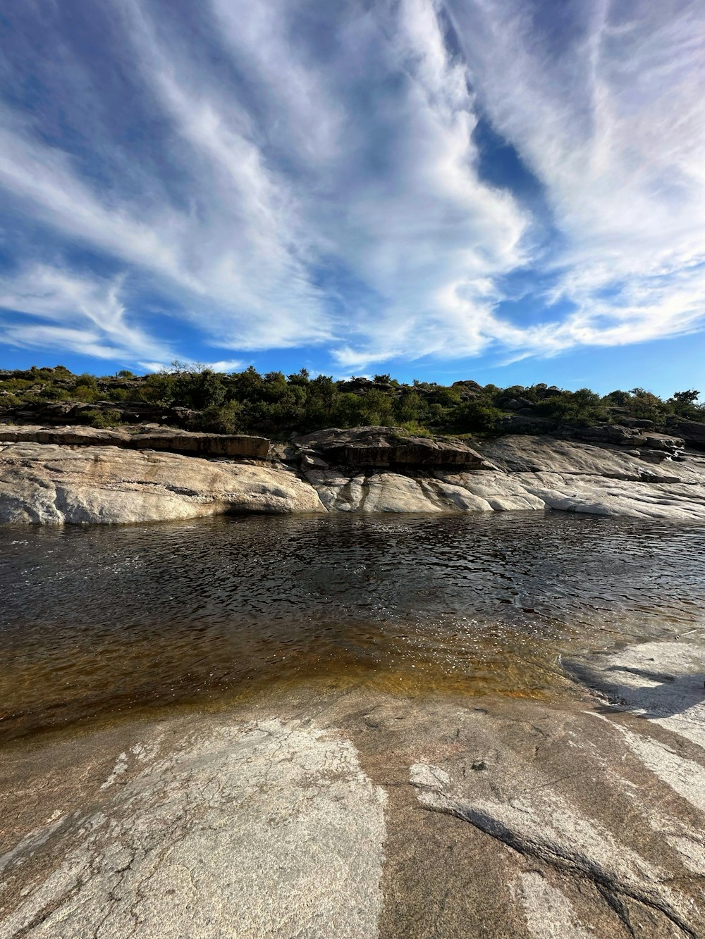 a man standing on top of a large rock next to a river