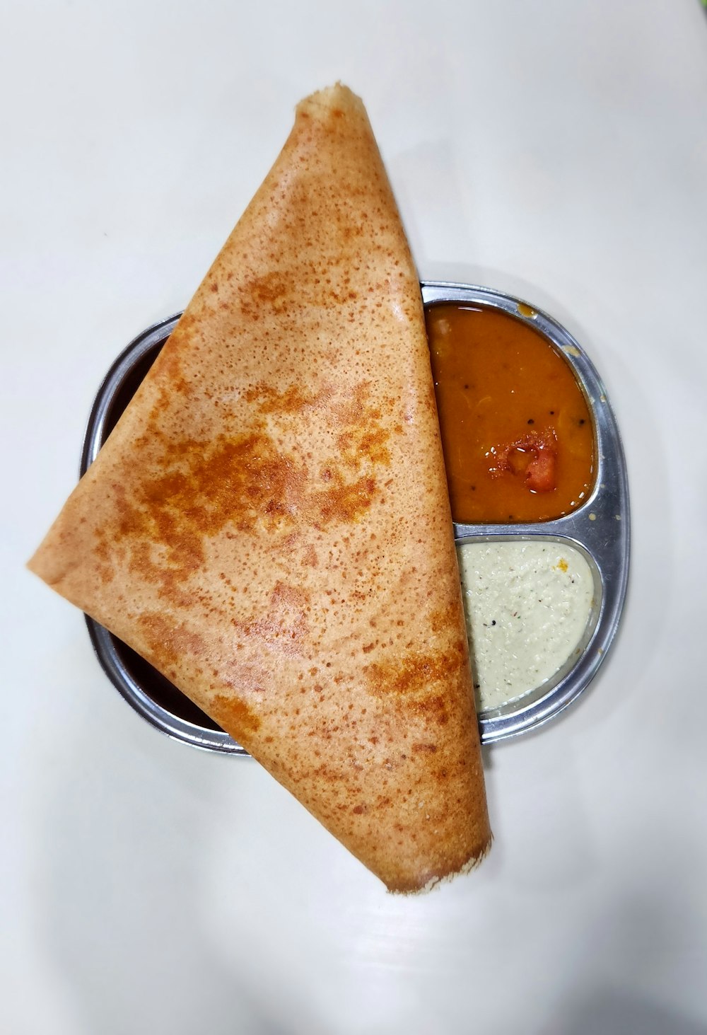 a plate with a pita and sauces on it