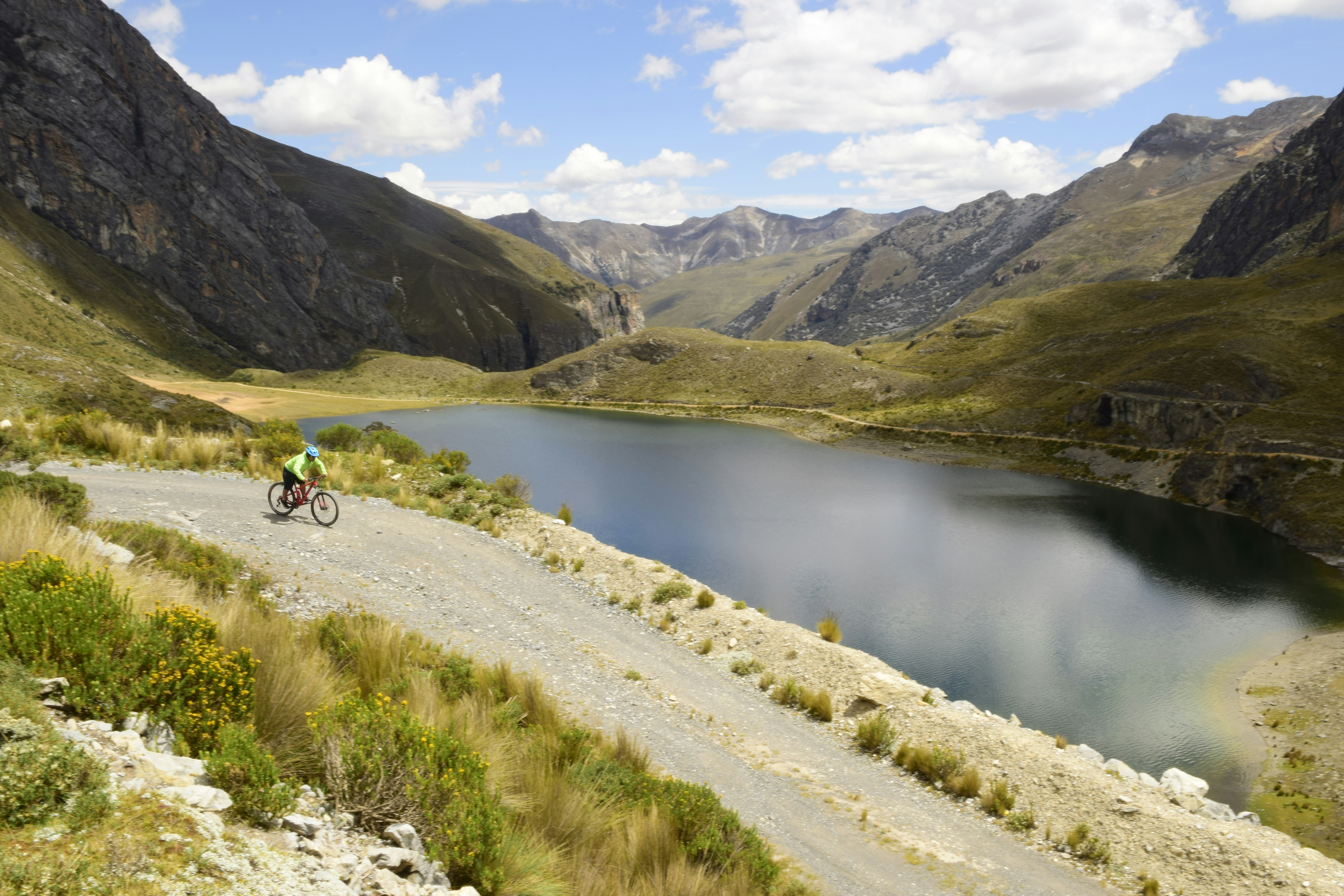 a man riding a bike down a road next to a lake