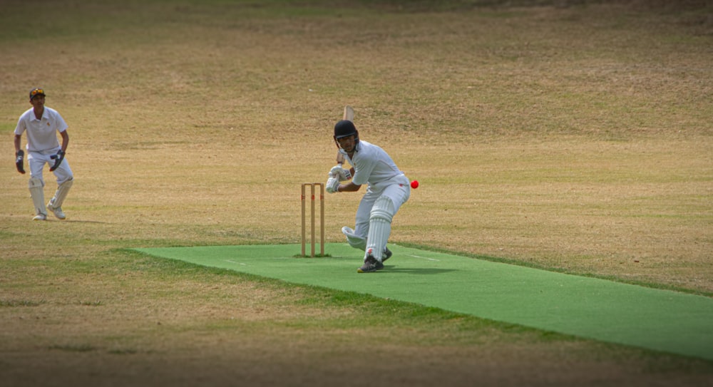 two men playing a game of cricket on a field