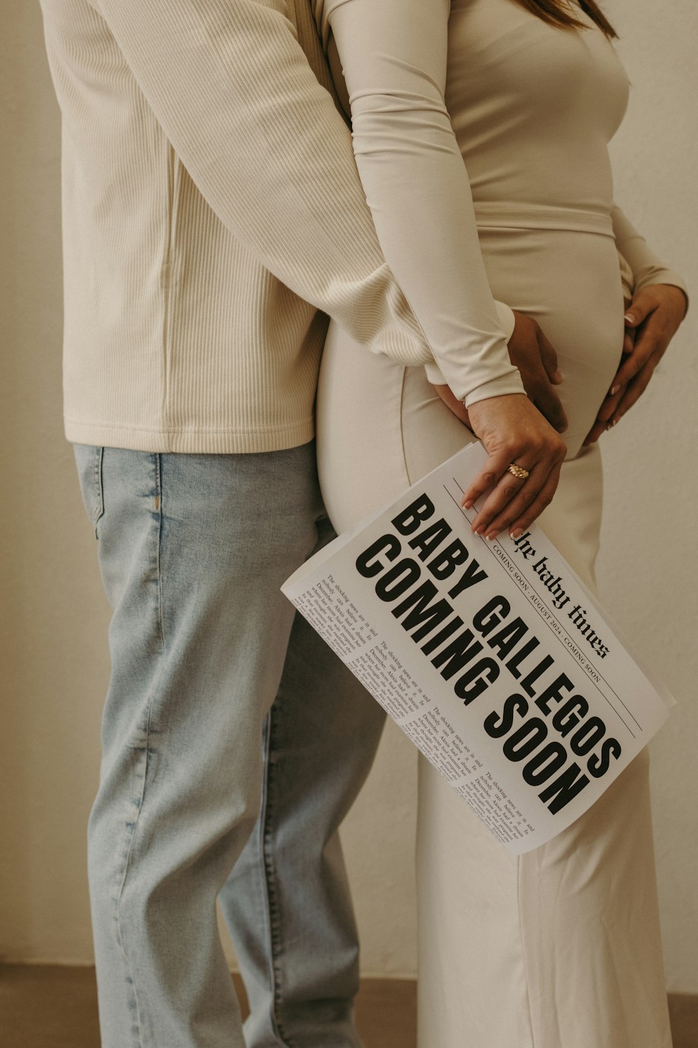 a pregnant woman holding a newspaper while standing next to a man