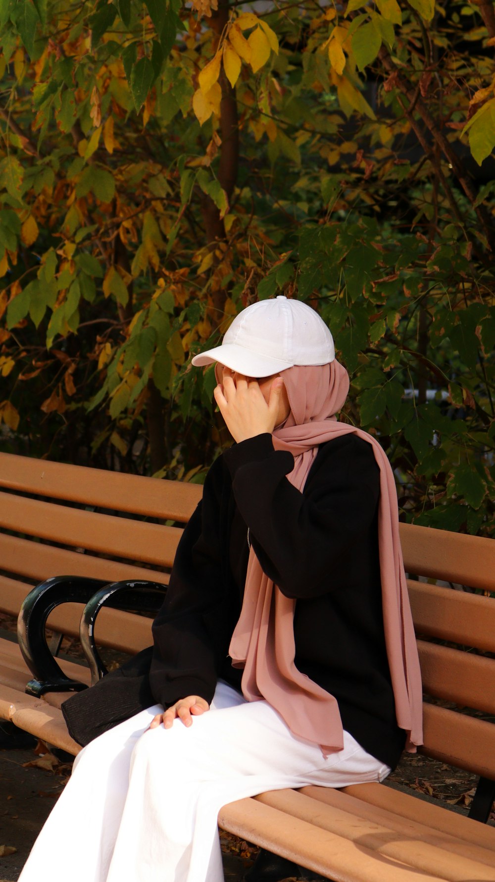 a woman sitting on a bench covering her face
