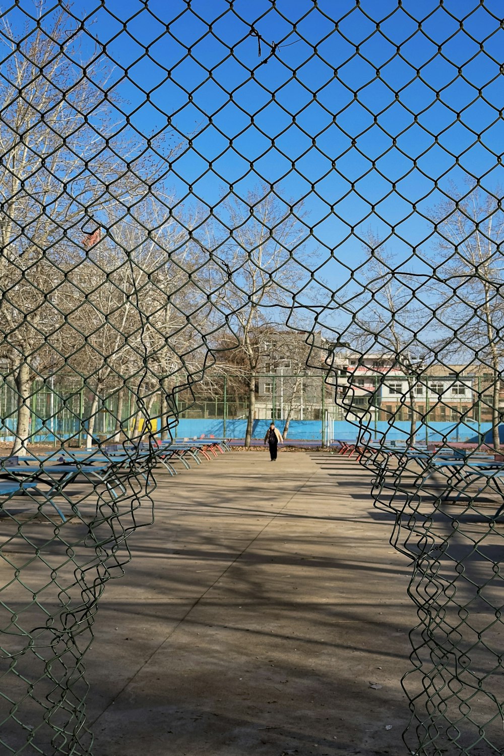 a person walking down a walkway through a fence